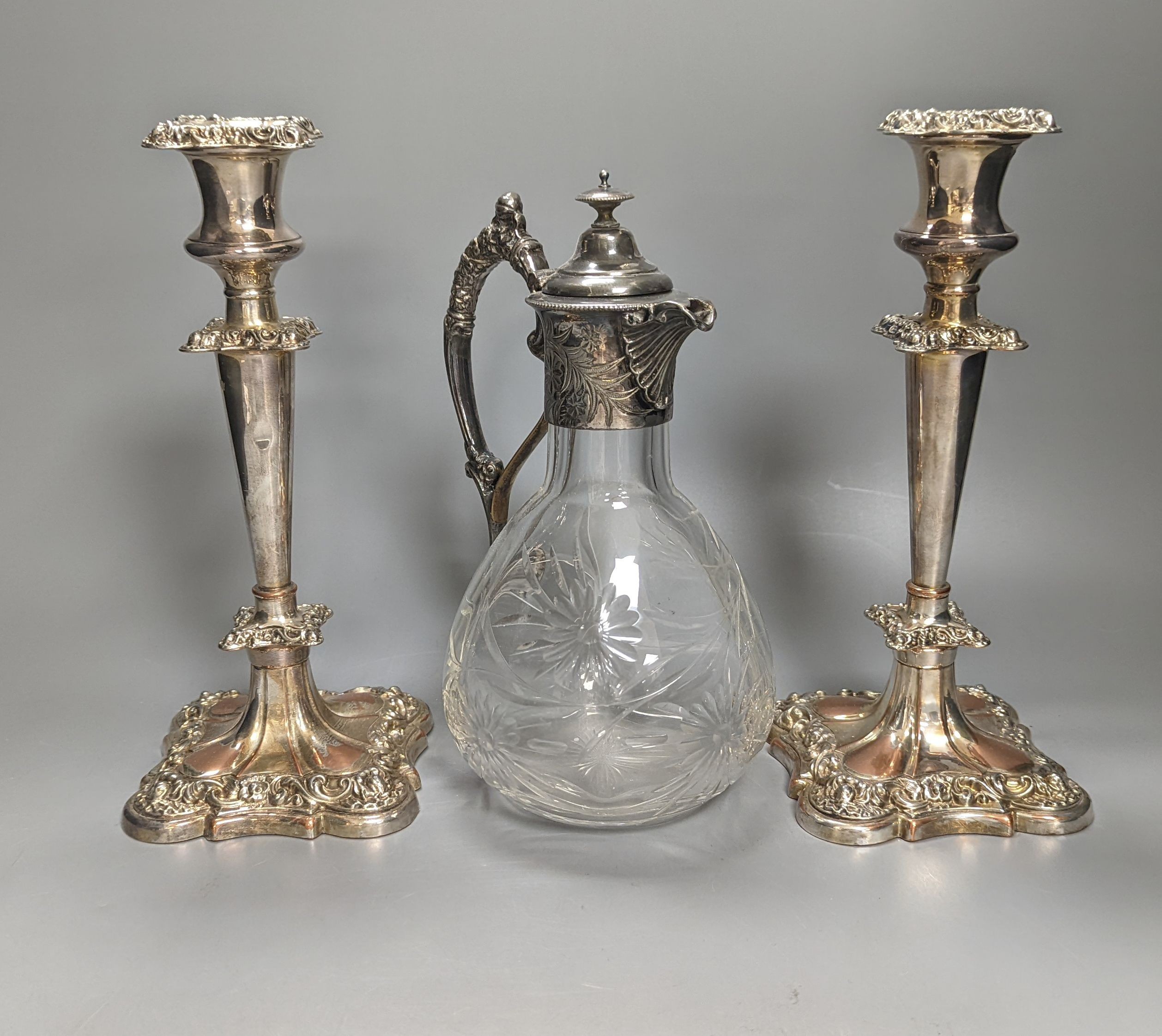 A Victorian electroplate mounted glass Claret jug, 23.5cm high and a pair of candlesticks